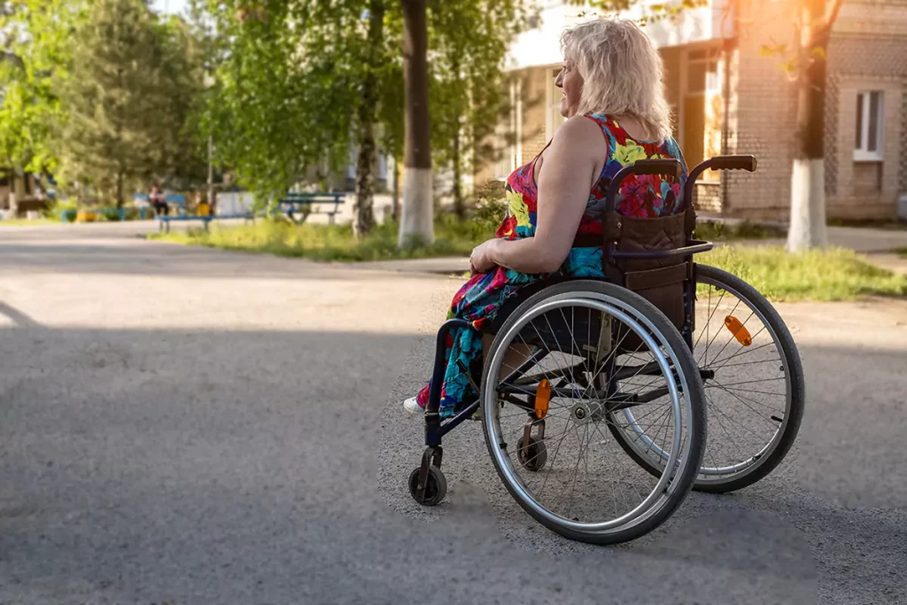 Paraplegic woman in wheelchair is smiling while going through a park